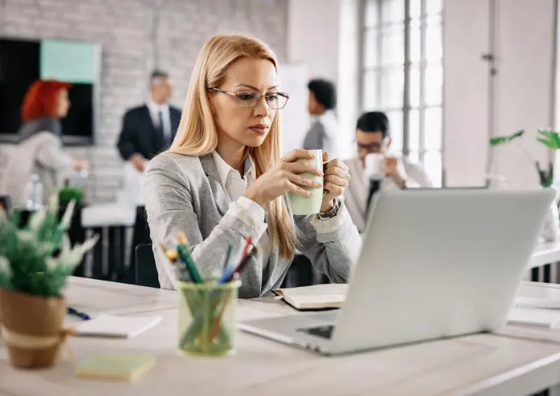 Businesswoman focused on laptop while holding a coffee business directory